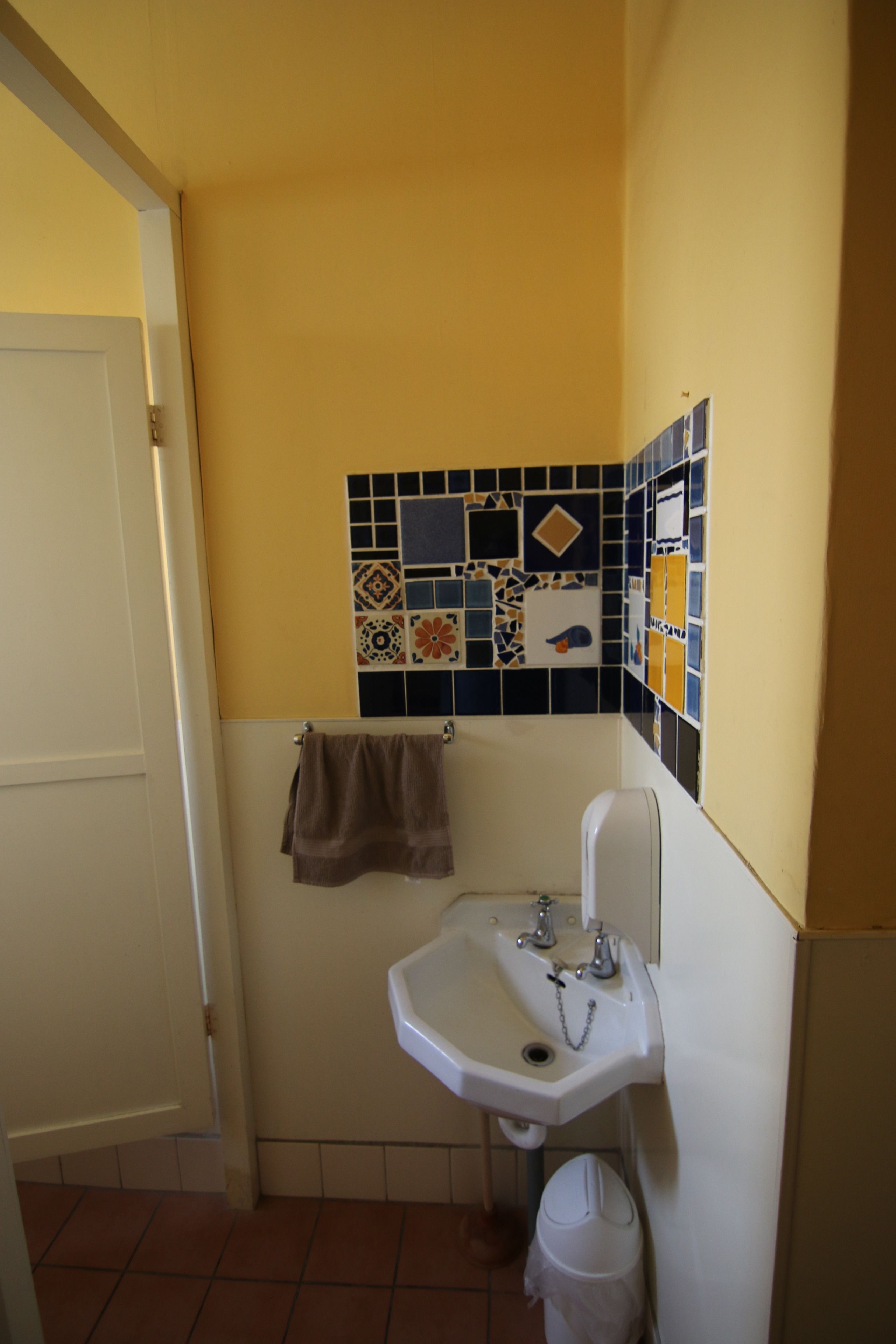 Une salle de bain avec un lavabo blanc, une serviette accrochée au mur et des toilettes.