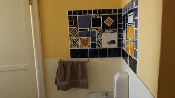 Une salle de bain avec un lavabo blanc, une serviette accrochée au mur et des toilettes.