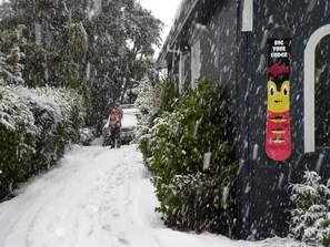 En snøklædt boligvej med et hus, der har et snowboard-skilt på døren.