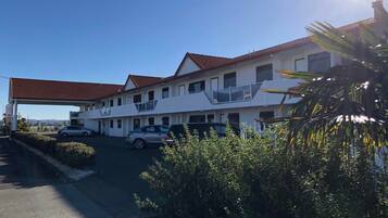 Un motel con una estructura de dos pisos, una zona de estacionamiento techada y vistas del paisaje circundante.