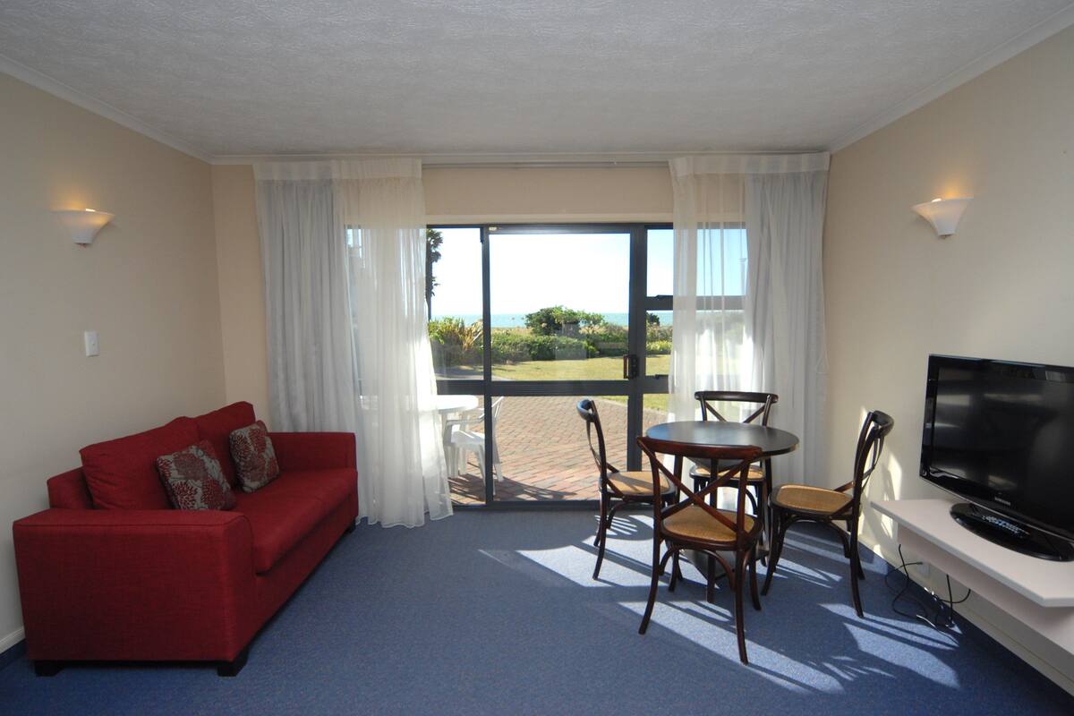 A room with a red sofa, a television, and a table with chairs.