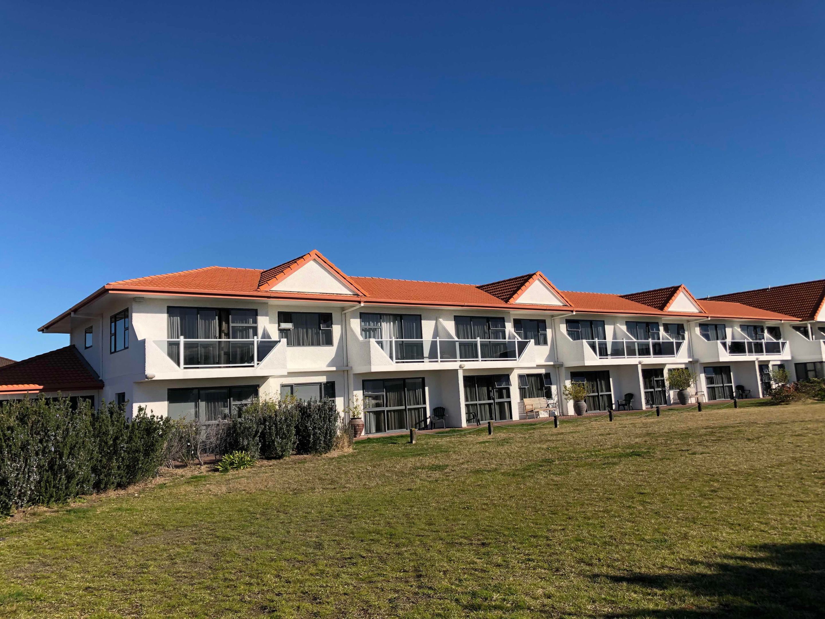 A multi-story hotel with a red-tiled roof, large windows, and a well-maintained lawn.
