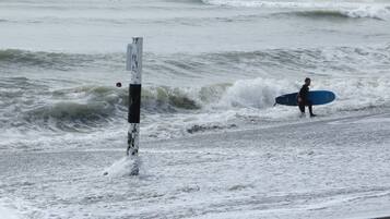 Une plage avec des vagues et un surfeur qui porte une planche de surf.