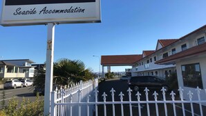 Letrero que indica 'Harbour View Seaside Accommodation' con una valla blanca al frente.