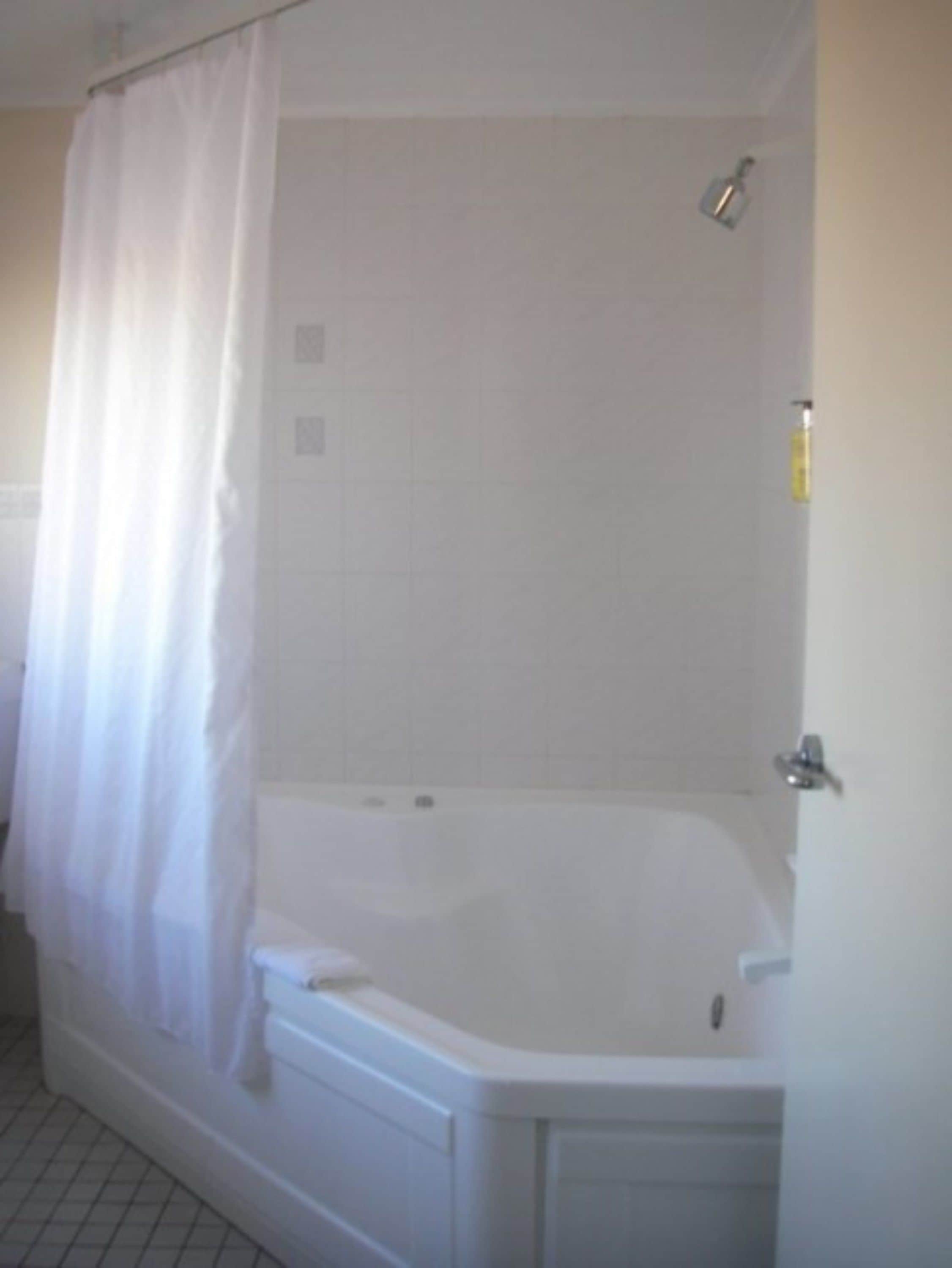 A standard white bathroom with a bathtub, a shower curtain, and a tiled wall.