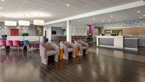 A spacious lobby with a reception desk, seating area with patterned chairs, and a coffee station. - Home2 Suites by Hilton Florence, SC (Florence)