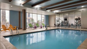 An indoor swimming pool with lounge chairs and exercise equipment. - Home2 Suites by Hilton Florence, SC (Florence)