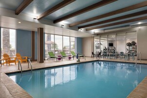Una piscina interior con sillas de descanso y equipo de ejercicio.