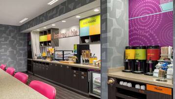 Una cafetería moderna con mostrador, zona de estar y máquinas de café.