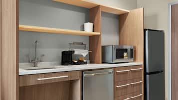 A modern kitchen with a stainless steel refrigerator, a microwave, a coffee maker, and wooden cabinets.