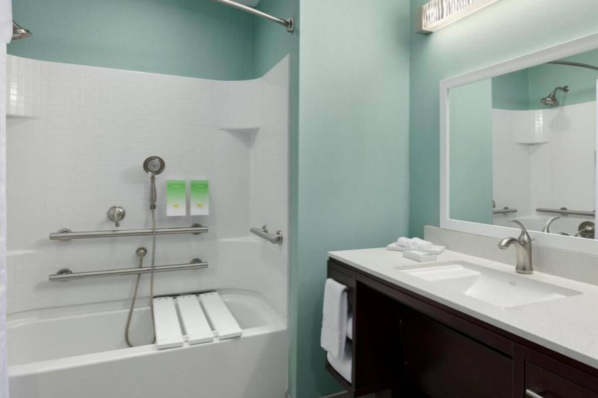 A modern bathroom with a bathtub, shower, and dual sinks.