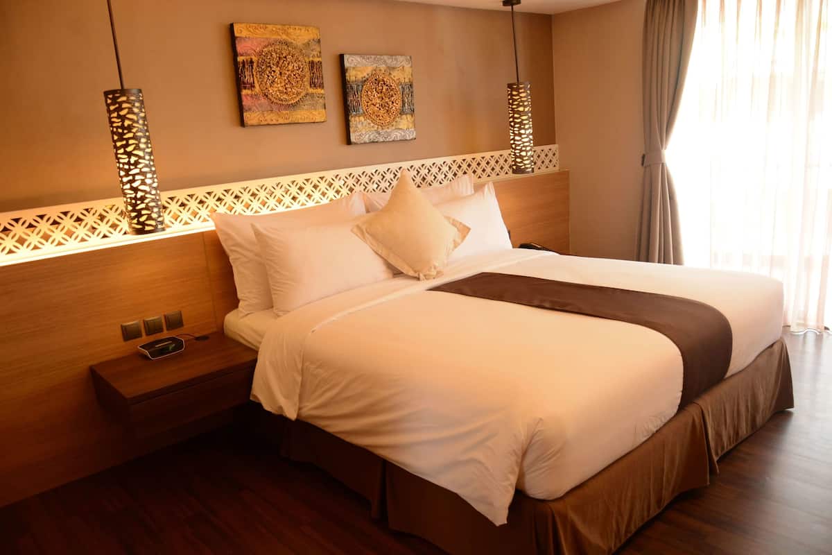 Habitación de hotel con una cama grande, cabecero de madera, decoración en la pared y una mesita de noche con un teléfono.