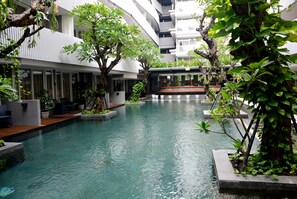 A serene indoor pool area with a modern architectural design, surrounded by lush greenery and seating areas. - Ramada by Wyndham Bali Sunset Road Kuta (Denpasar)