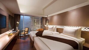 Ein Hotelzimmer mit einem großen Bett, einem Schreibtisch und einem Stuhl. Ein großes Fenster mit Vorhängen und ein dekoratives Wandbild über dem Bett.