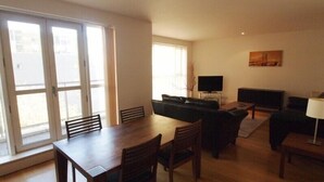 Un amplio salón con una mesa de comedor, sillas, un sofá, un televisor y una lámpara.