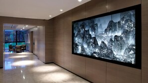 A modern lobby with a large digital display of a mountainous landscape.