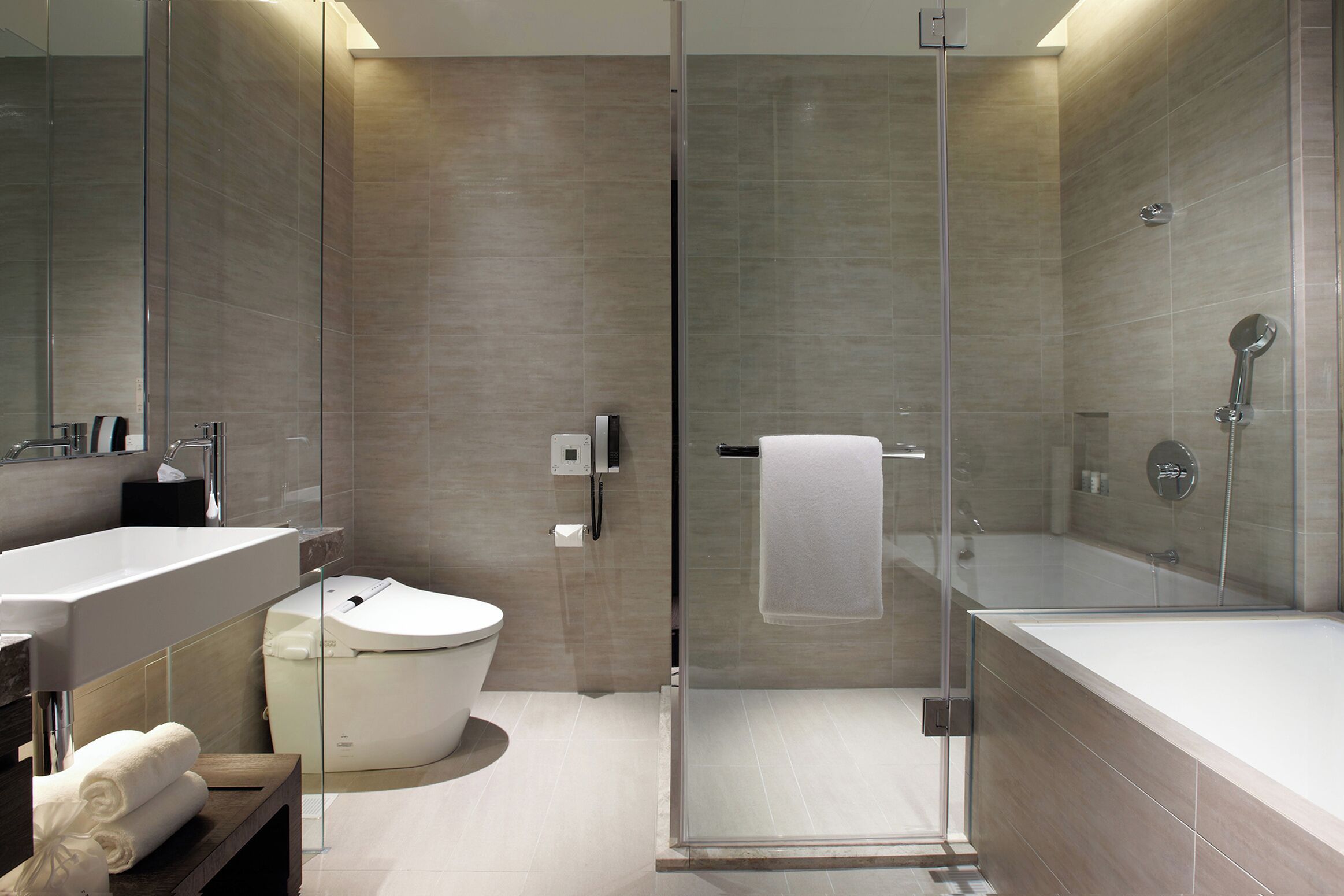 A modern bathroom with a glass-enclosed shower, a white bathtub, and a toilet.