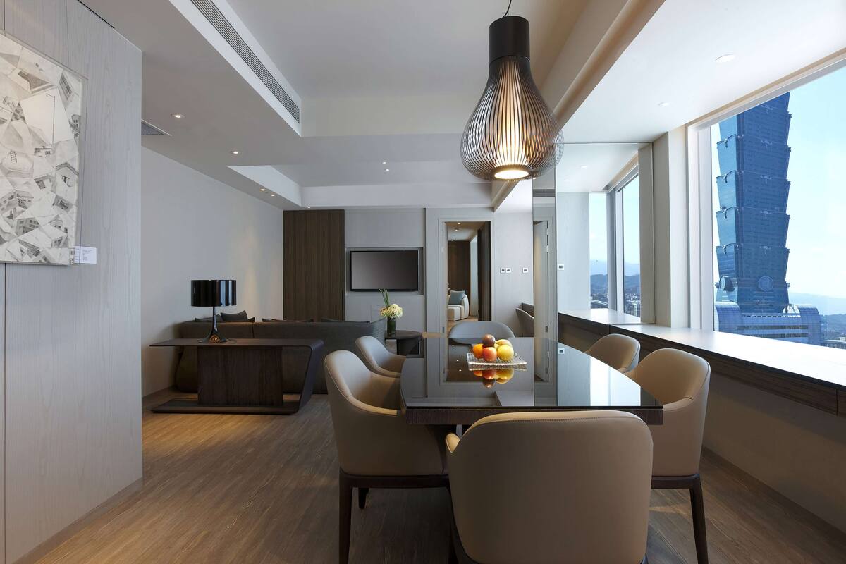 A modern dining area with a large table, chairs, and a unique pendant light.