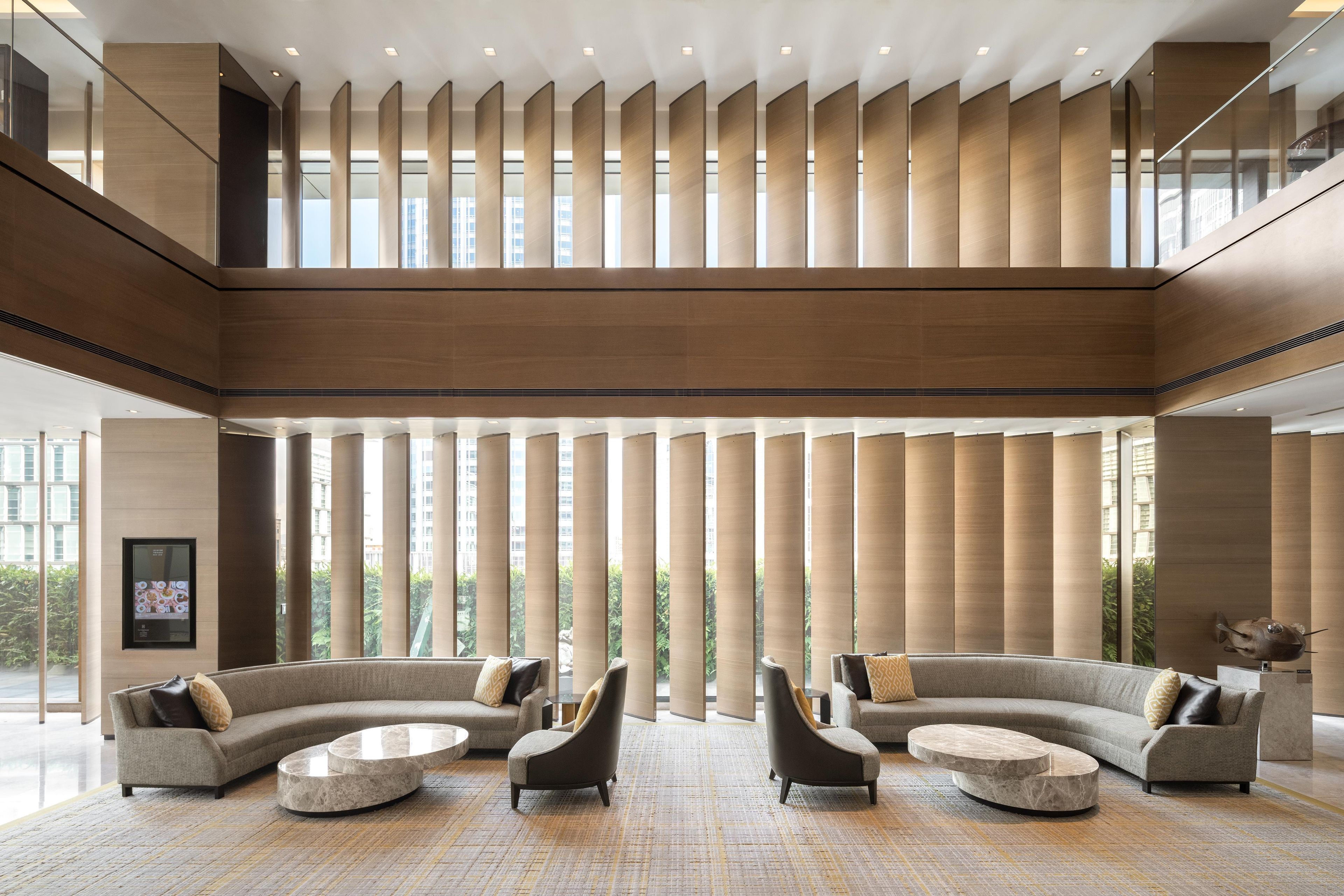 A spacious lobby with high ceilings, a mezzanine level, and a view of greenery outside.