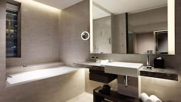 A modern bathroom with a large bathtub, a vanity with a mirror, and a towel rack.