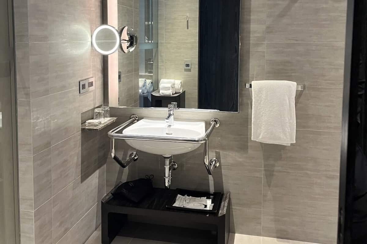 A modern bathroom with a large mirror, a sink, and a towel rack.