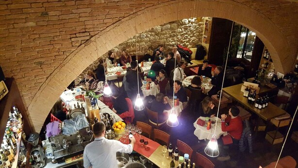 Vilkkaasti asiakkaita täynnä oleva ravintola, jossa on tiiliseinät sekä useita pöytiä ja tuoleja.