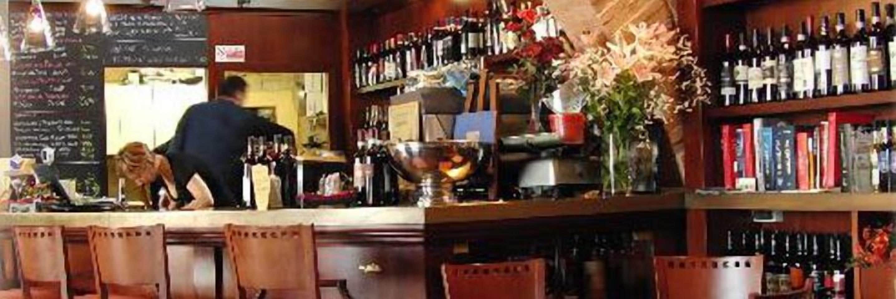 A bar with a counter, chairs, and shelves of bottles.