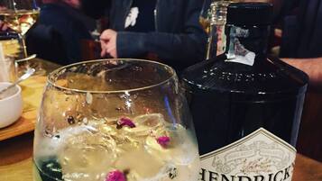 Une bouteille de gin Hendrick's et un verre contenant des glaçons et des pétales de fleurs.