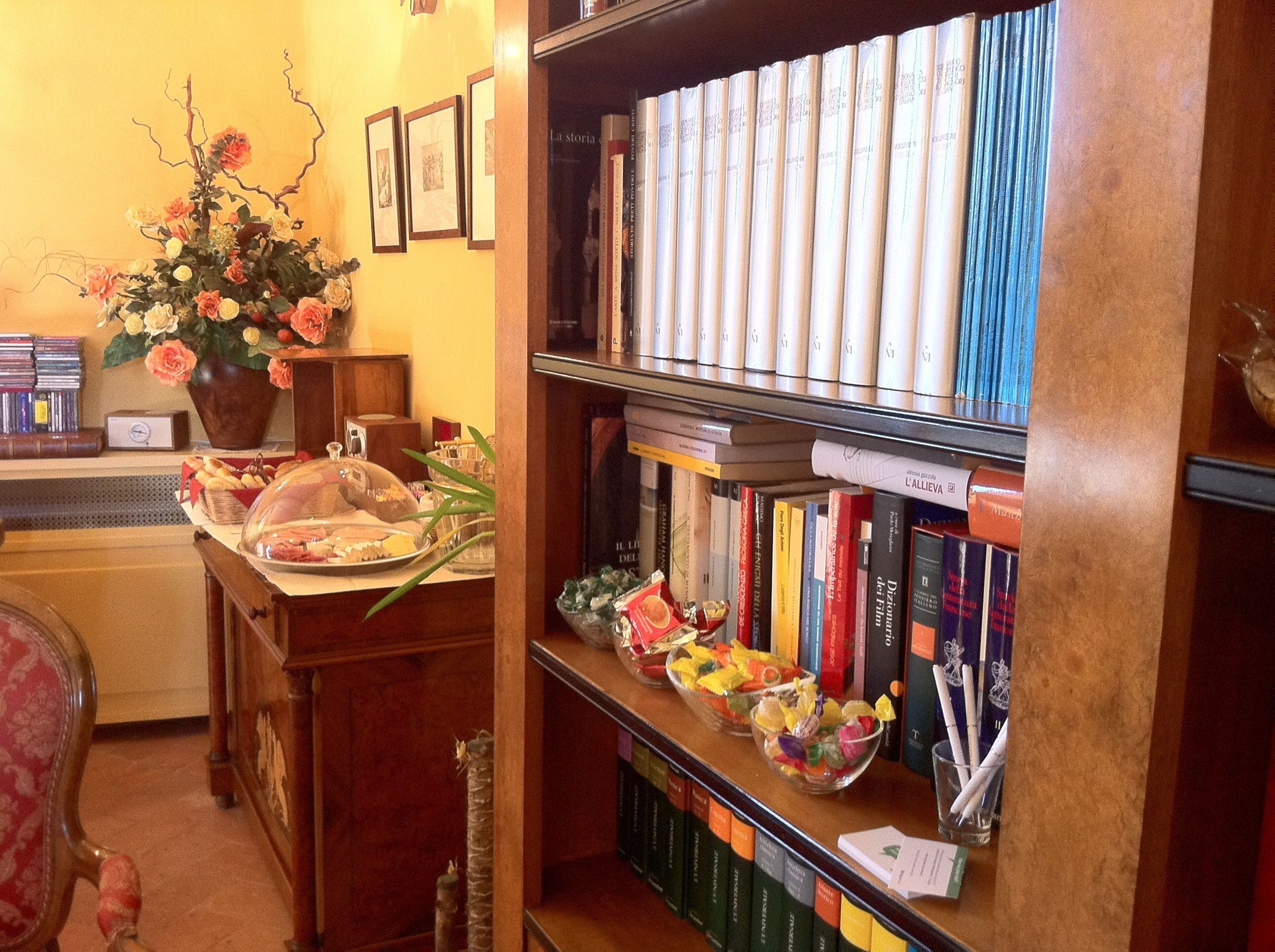 Een bibliotheek met boekenplanken, een bloevas en een tafel met etenswaren.