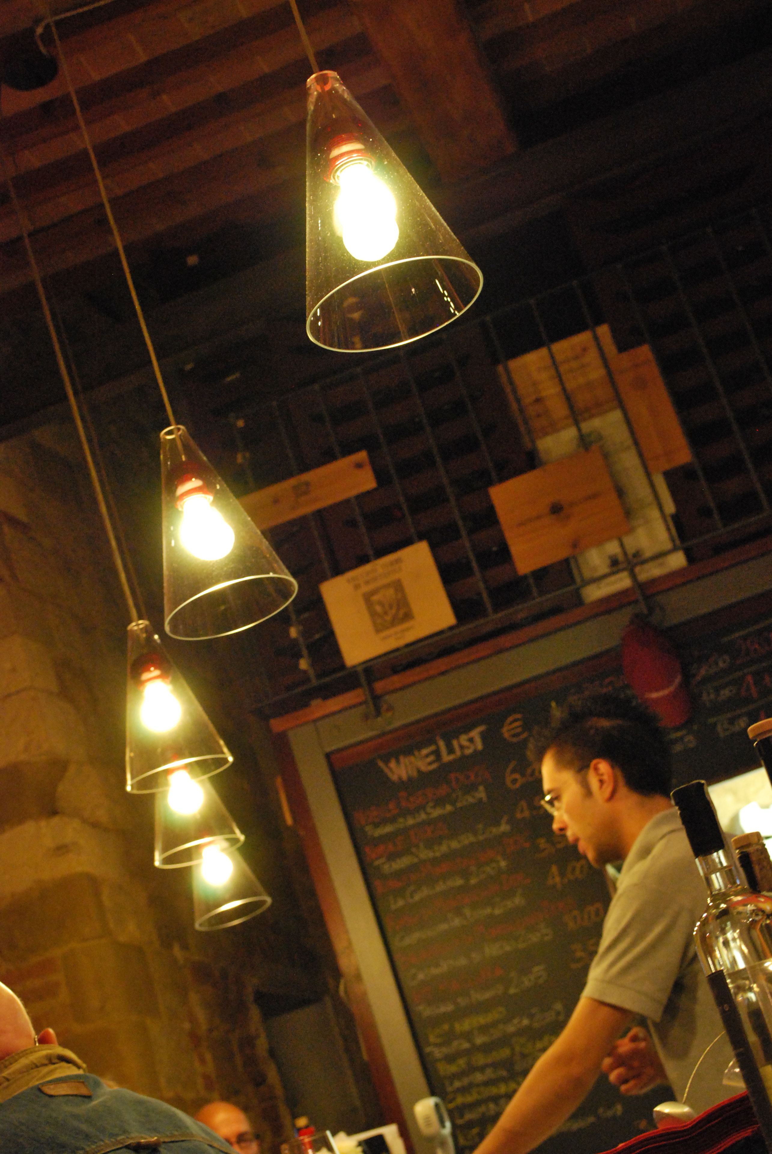 A restaurant interior with hanging light fixtures and a chalkboard menu.