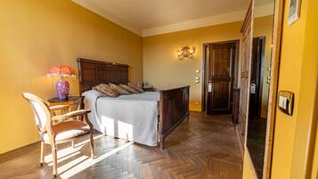 A bedroom with a wooden bed, a chair, a lamp, and a mirror.