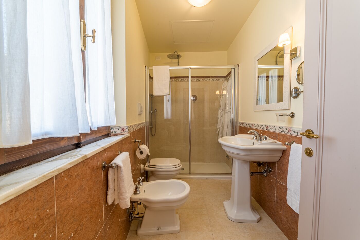 Ein Badezimmer mit Toilette, Bidet, Waschbecken und einer Duschkabine.