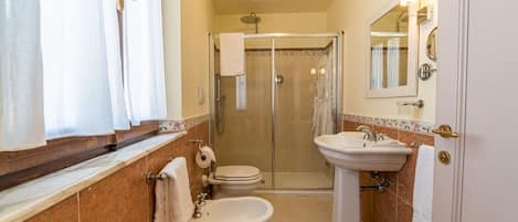 Ein Badezimmer mit Toilette, Bidet, Waschbecken und einer Duschkabine.