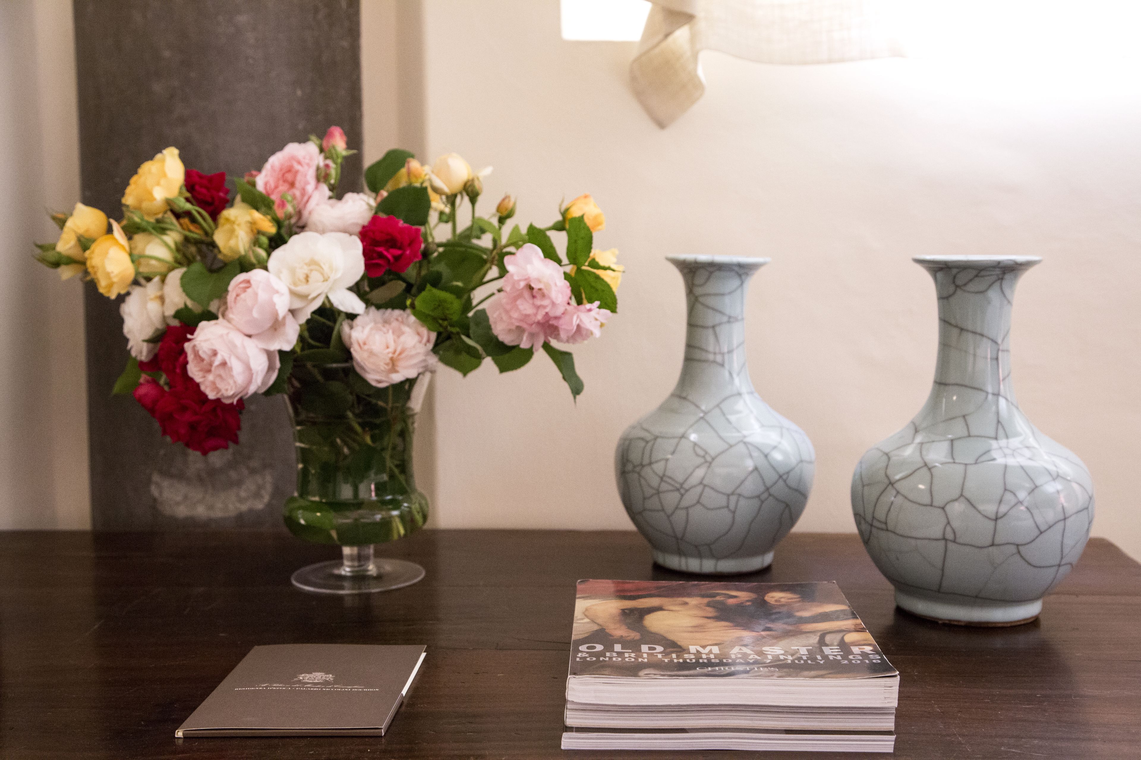 Une table avec un vase de fleurs, deux vases et un livre.