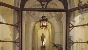 Eine prachtvolle Eingangshalle mit einer Marmortreppe, die zu einer Statue führt, eingerahmt von Glastüren und einer Fußmatte.