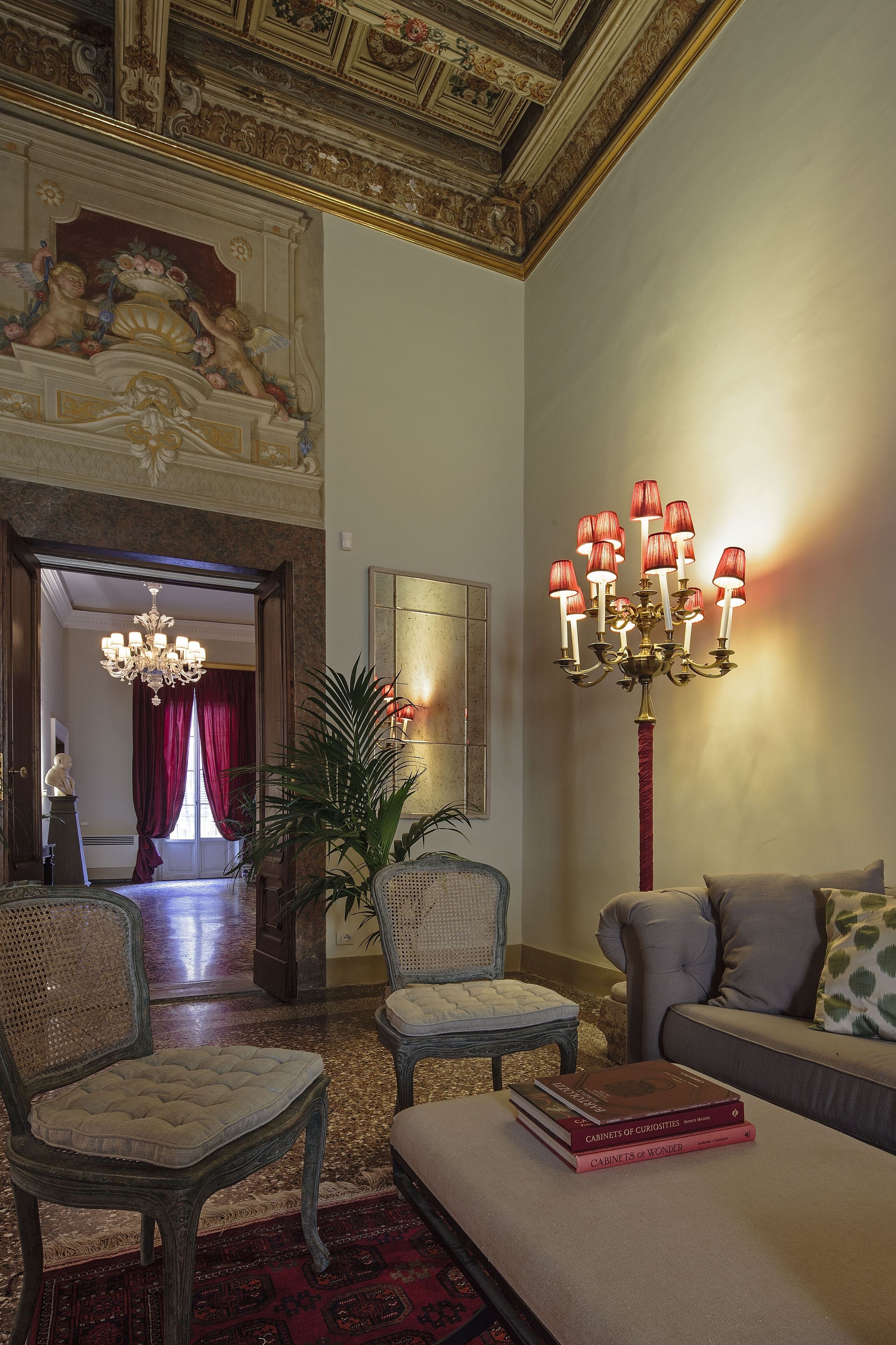 A grand room with a chandelier, a sofa, and a chair with a book on it.