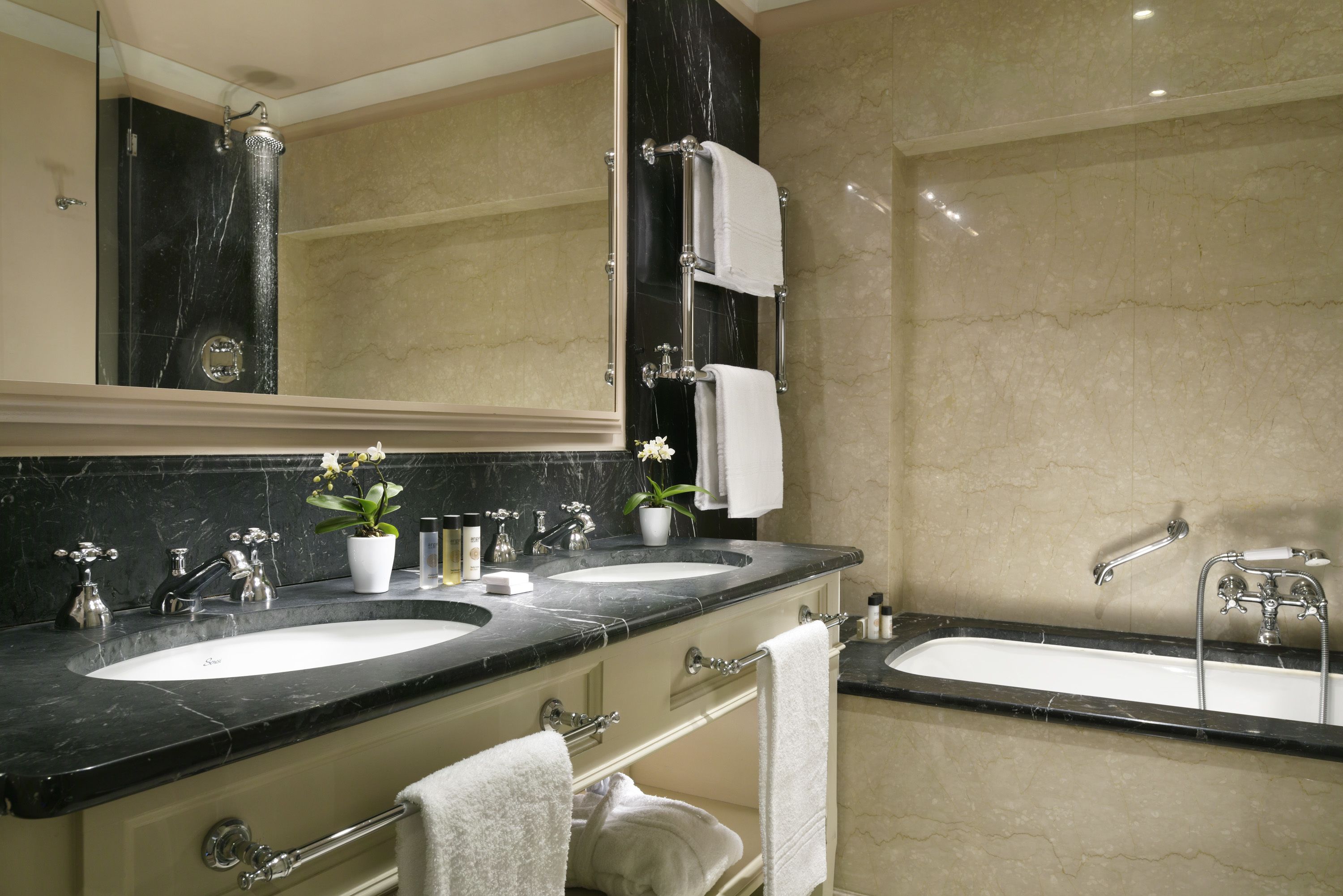 Une salle de bain avec deux lavabos, une baignoire et un grand miroir.