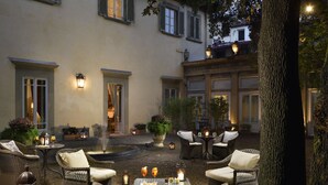 Eine Außenpatio mit Korbmöbeln, einem Springbrunnen und stimmungsvoller Beleuchtung.
