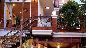 A multi-level building with a brick facade, a central staircase, and a pathway surrounded by lush greenery. - Wheel Garden Riverside (Siem Reap)