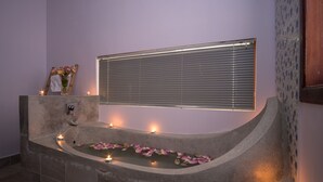 A spa area with a stone bathtub, candles, and a window with blinds. - Wheel Garden Riverside (Siem Reap)