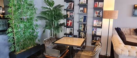 Un salon moderne comprenant un canapé, une table basse, des fauteuils, une bibliothèque et une grande plante en pot.