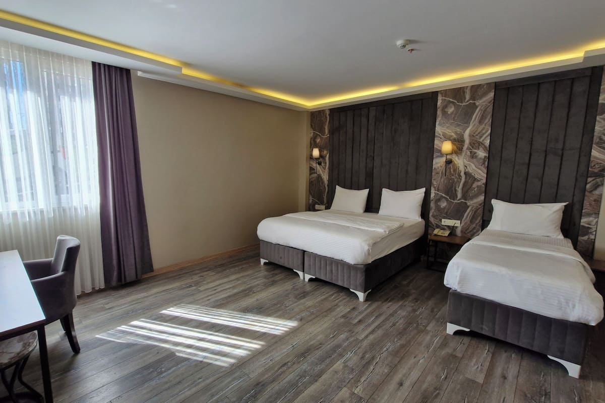 A hotel room with two beds, a desk, and a chair.