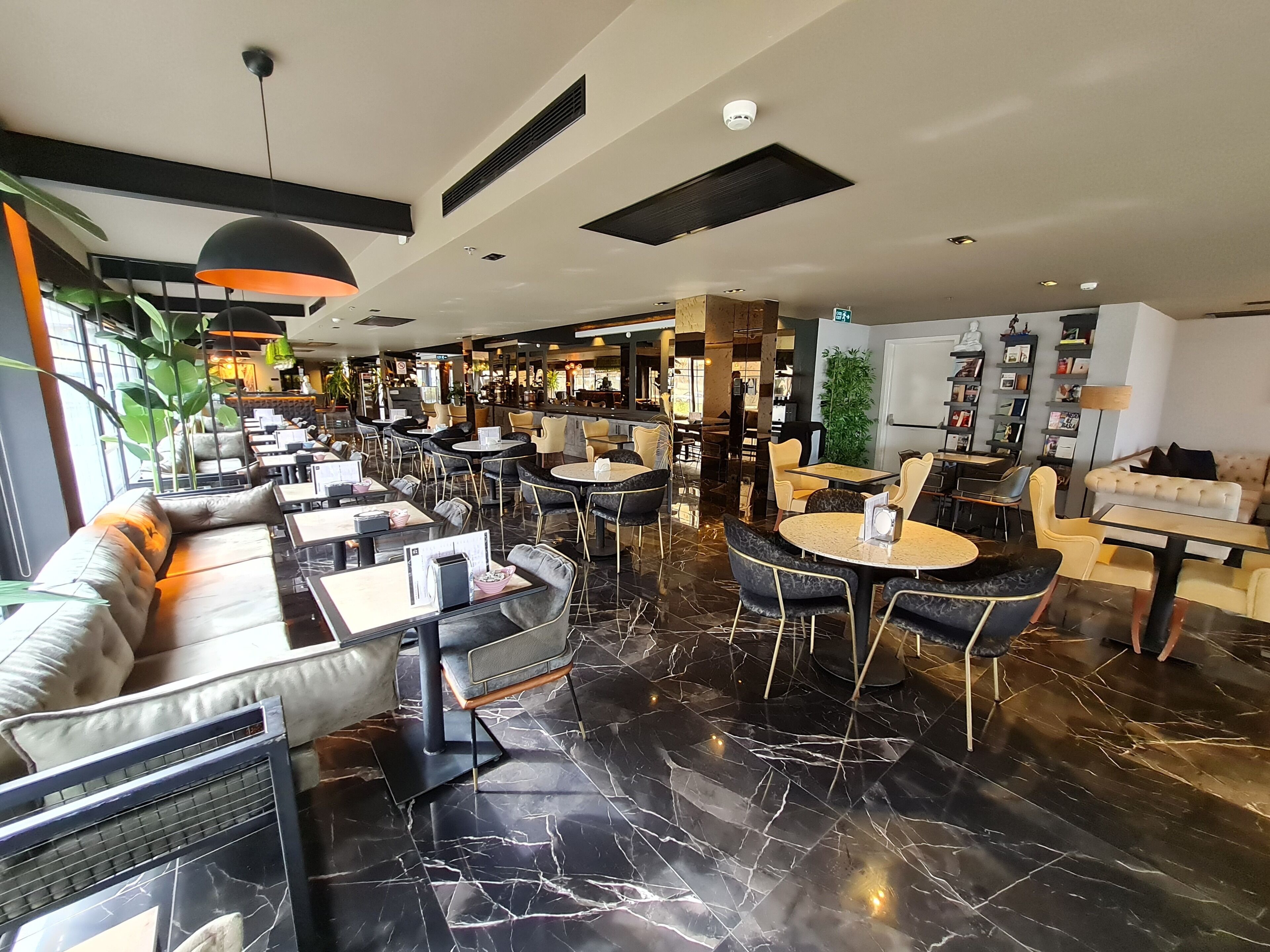 Un ristorante moderno con pavimenti in marmo nero, tavoli rotondi e sedie di colore nero e giallo.