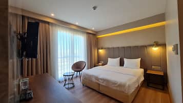 Una habitación de hotel con una cama, una silla, una mesa y un televisor.