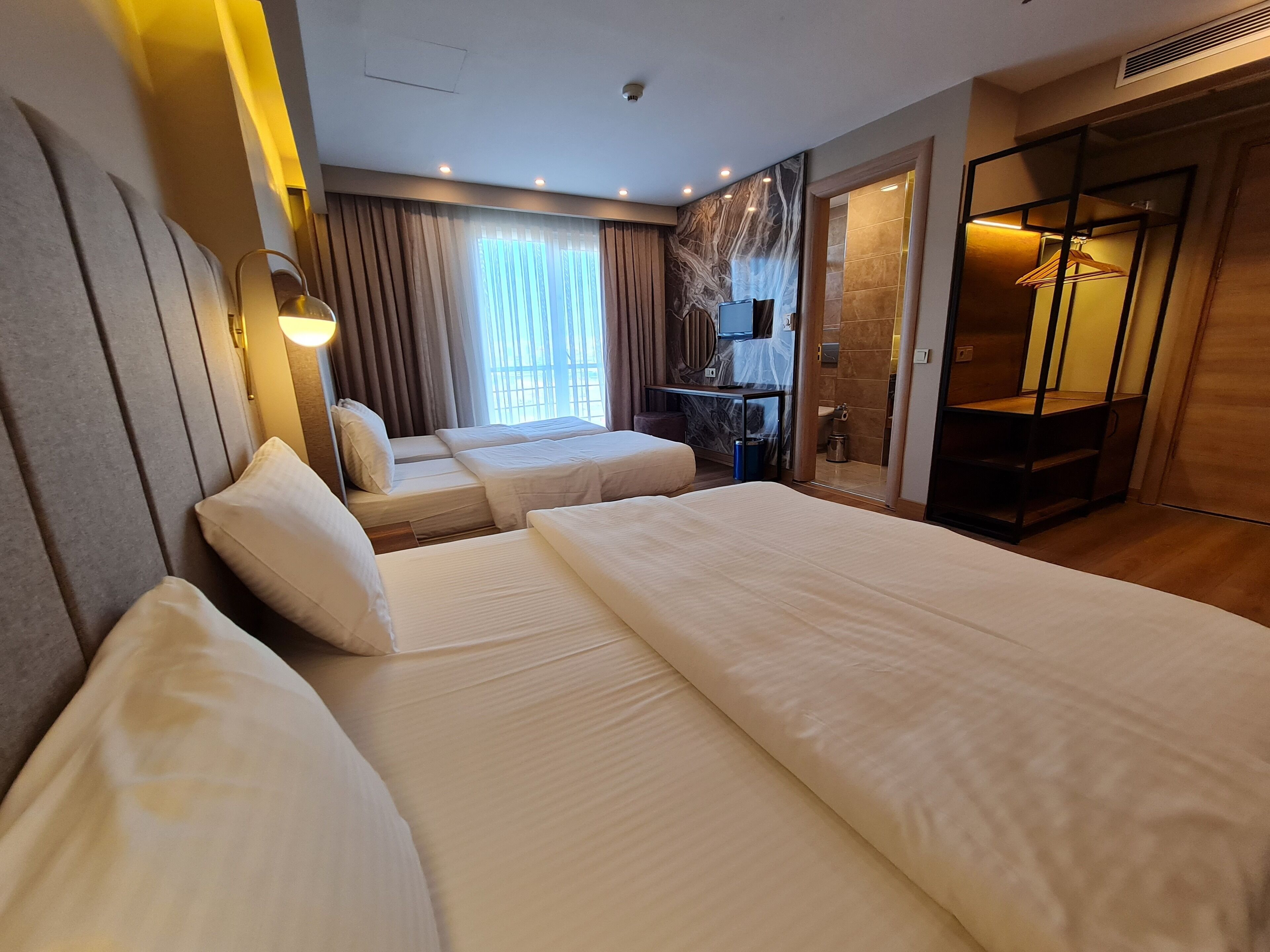 A hotel room with two beds, a shower area, and a wardrobe.