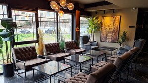 A modern lounge area with leather sofas, glass tables, and large windows offering views of the street.