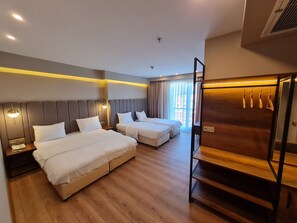 Une chambre d’hôtel avec deux lits, un plancher en bois, une armoire en bois et une fenêtre avec des rideaux.