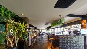 A modern bar area with marble flooring, seating, and a bar counter.