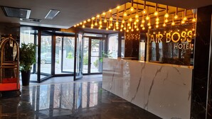 A hotel reception area with a marble floor, glass doors, and a sign reading "AIR BOSS HOTEL".