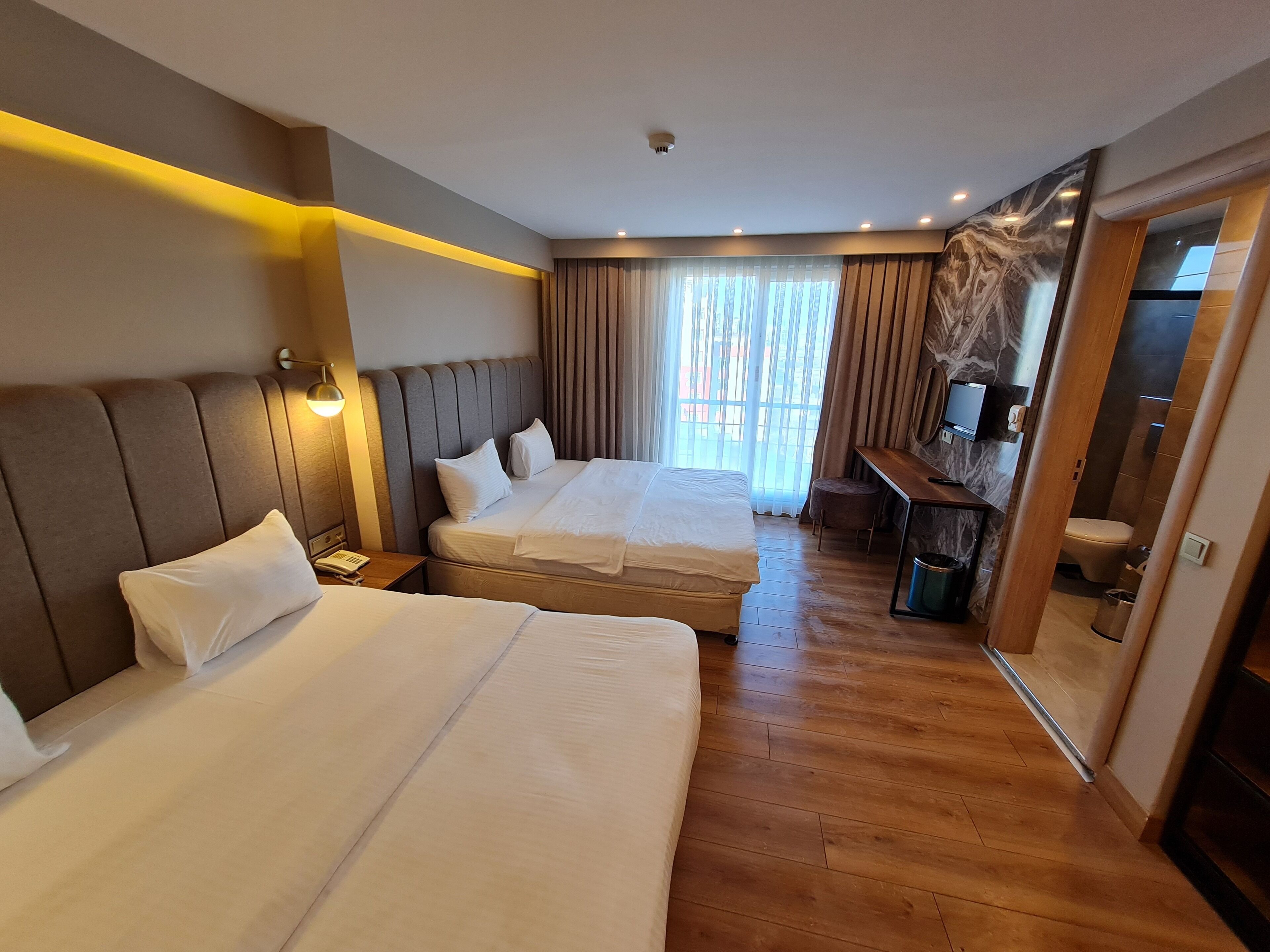 Een hotelkamer met twee bedden, een bureau, een televisie en een badkamer.